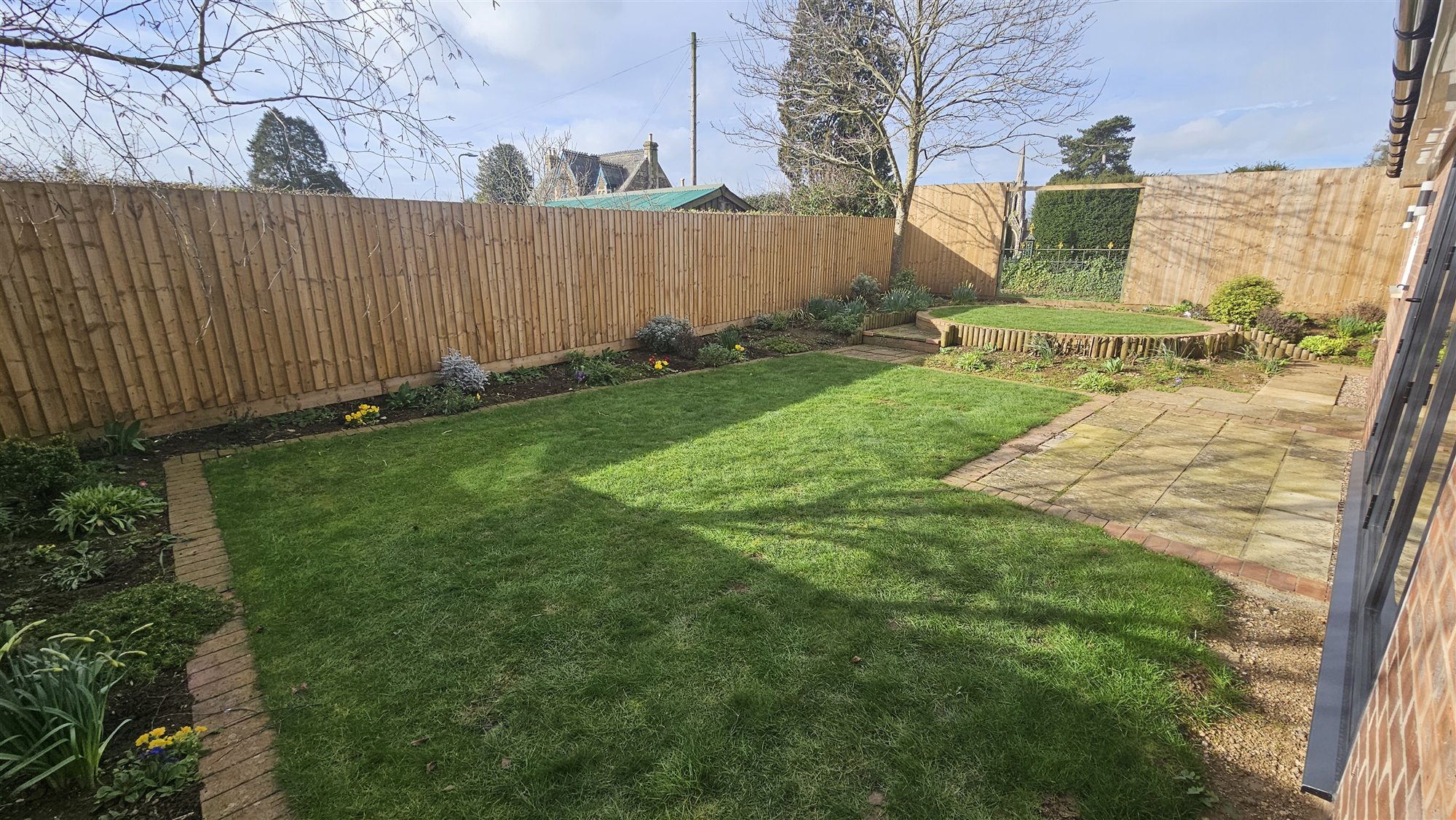 Large porcelain entertaining terrace and raised planting after transformation